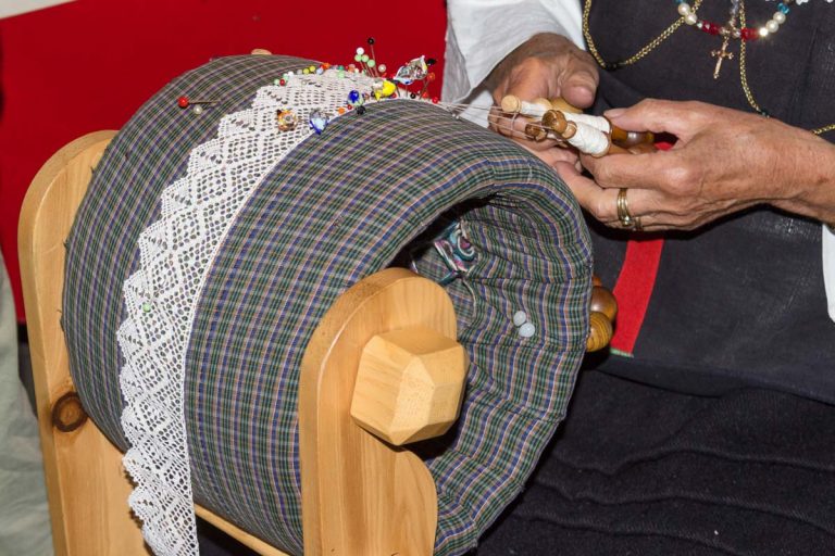 COGNE, ITALY - AUGUST 24, 2016:  Woman in traditional clothes is making a typical handicraft (tombolo) during a popular festival in the village of Cretaz