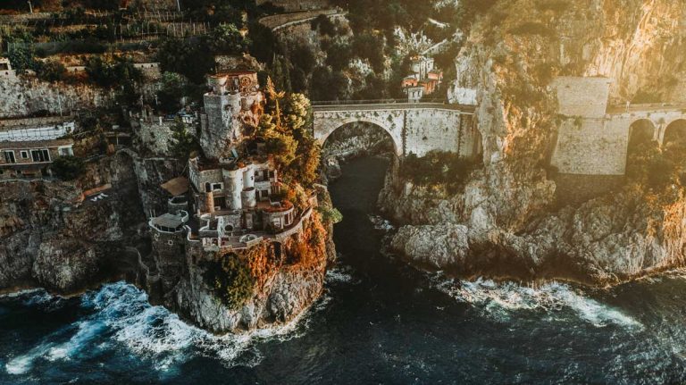 Top aerial view of famous fiordo di furore beach and bridge and his boats seen from birds eye in the beautiful Amalfi Coast in South Italy. Perfect wallpaper for drone and nature lovers.