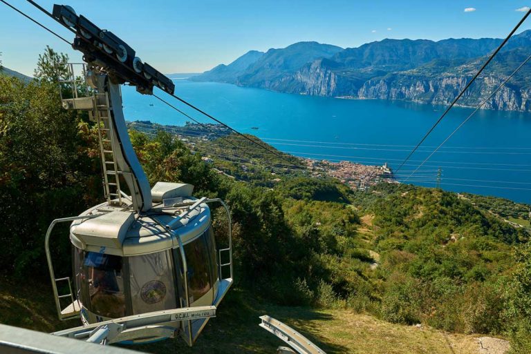 Monte Baldo,Lago di Garda ,Italy -4 October 2018:Cable car with the rotating cabins transporting passengers to Monte Baldo mountain, Lake Garda and the town of Malcesine in the back,Garda Lake,Italy