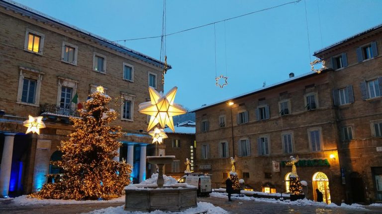 URBINO, ITALY - DECEMBER 17, 2018: Main square of Urbino decorated with christmas tree and stars with snow at dusk