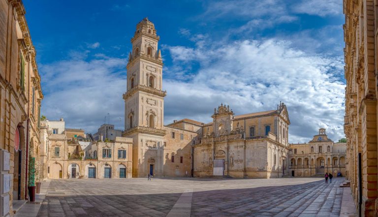 Panorama of Piazza del Duomo square , Campanile tower and Virgin Mary Cathedral (Basilica di Santa Maria Assunta in Cielo), Caritas Diocesana in Lecce - Puglia, Italy. Baroque city of Apulia