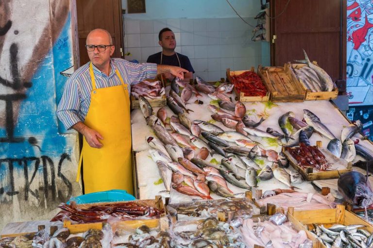 PALERMO, ITALY - OCTOBER 23, 2014: Customers and sellers buying and selling fish and sea products on Vucceria farmer's market on streets of old Palermo city center. It is most famous Palermo market.