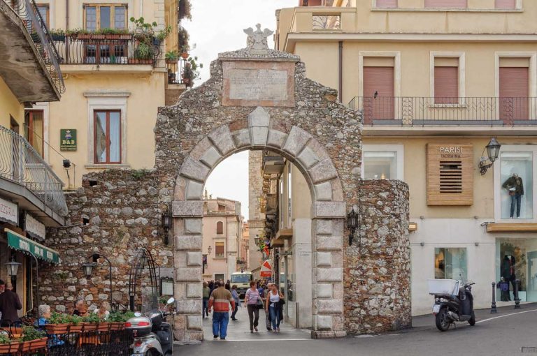 Locals and tourists pass through the Messina Gate (Porta Messina) at the northern end of Corso Umberto - Taormina, Sicily, Italy, 22 October 2011