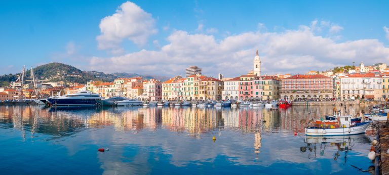 Imperia, Italy - December 31, 2019: Panoramic cityscape of Imperia from the port of Oneglia with buildings and boats reflected on water