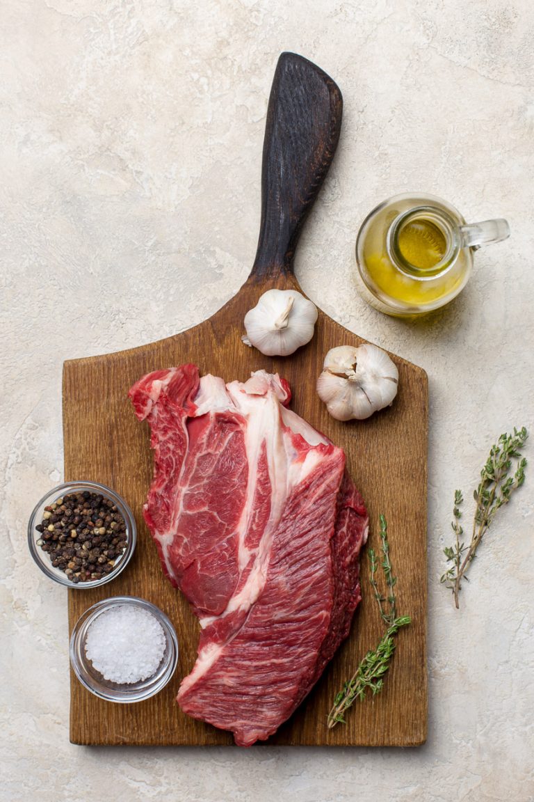 Raw cut of beef on wood board at light background. Concept of recipe food. Top view